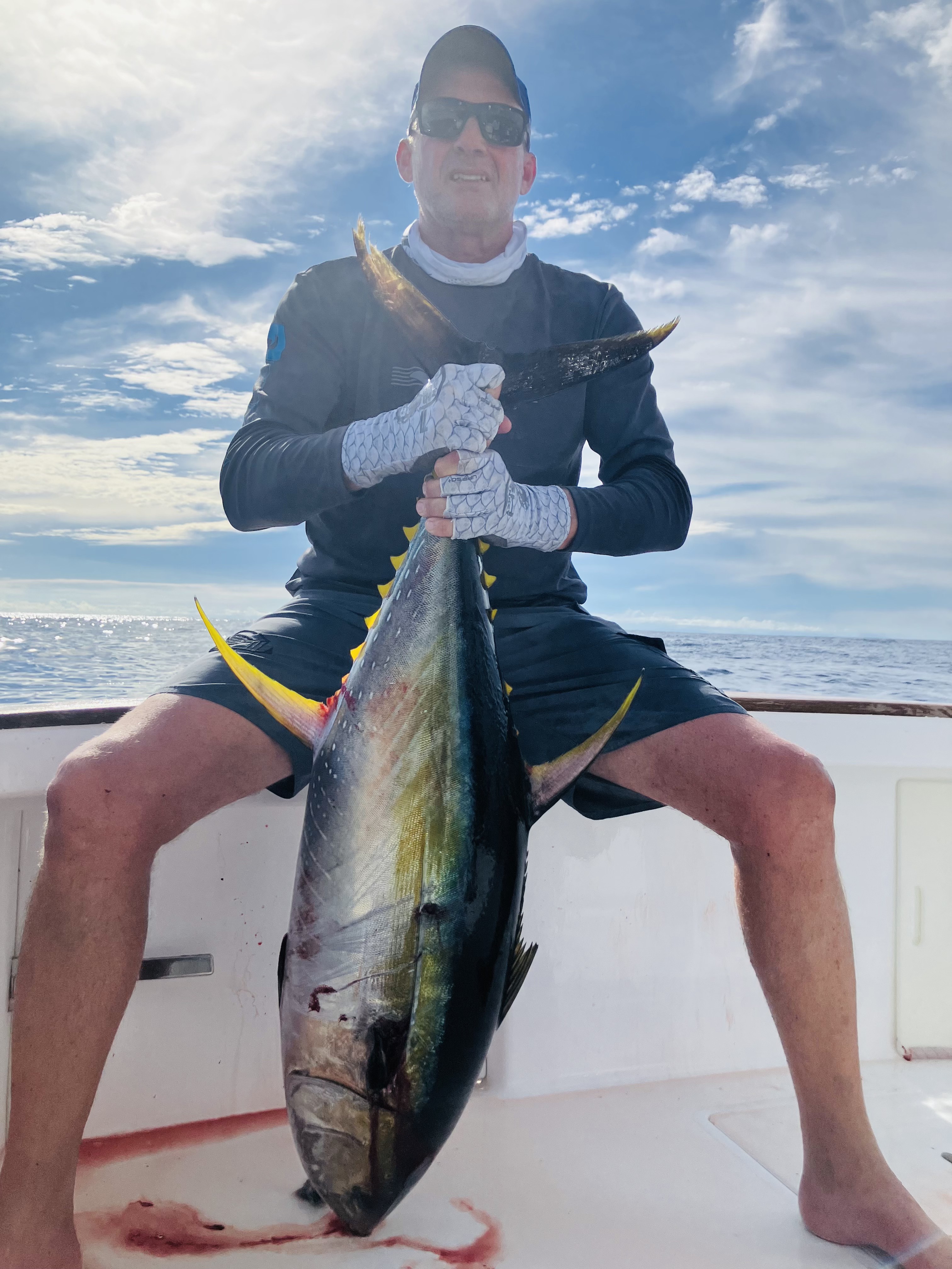 Angler holding a yellowfin tuna aboard Tiger Fly
